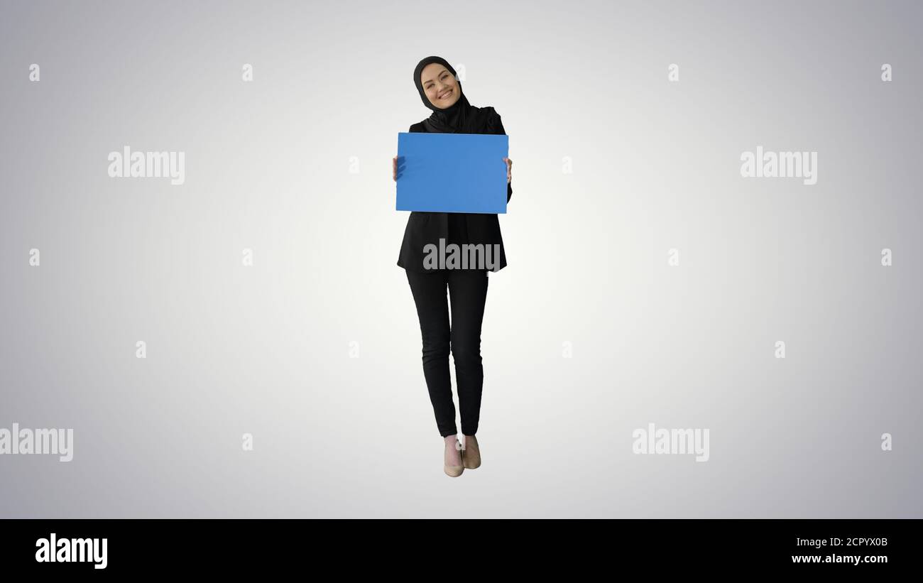 Smiling Arab woman in hijab holding blank blue poster and lookin Stock ...