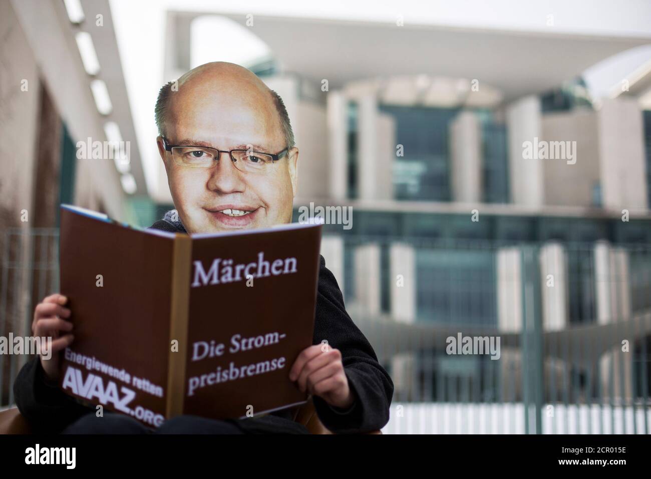 A environmental activist wearing a mask of Environment Minister Peter Altmaier pretends to read from a mock fairy tale book during protest against the government's handling of the energy transition in front of the Chancellery in Berlin, March 21, 2013.  German Chancellor Angela Merkel has invited Germany's state ministers to discuss the progress of Germany's transition to renewable energy. The writing on the book reads: 'Fairy tales. The Energy Prize Curtailment'.   REUTERS/Thomas Peter (GERMANY  - Tags: CIVIL UNREST POLITICS ENERGY) Stock Photo