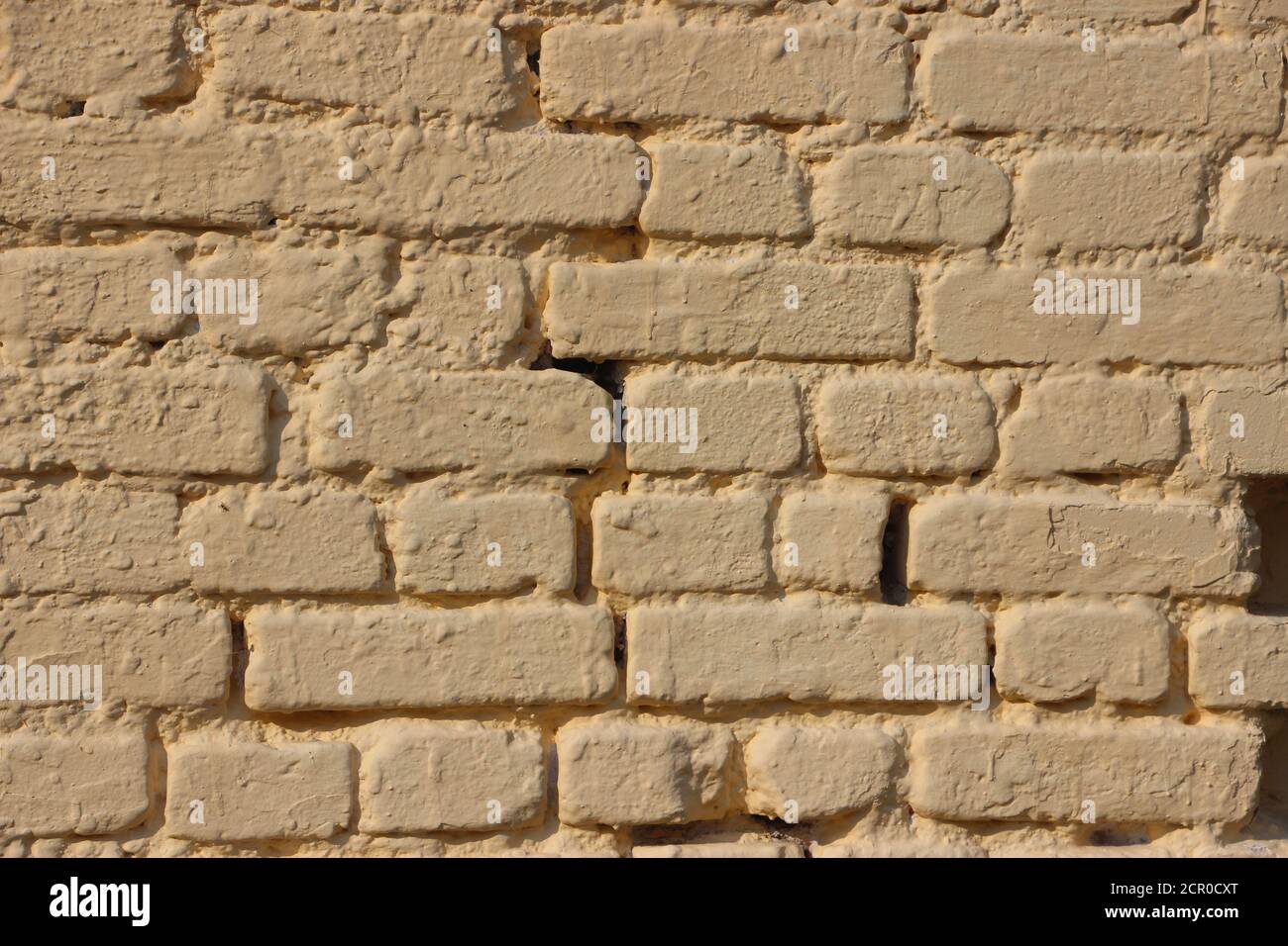 old gringe vintage weathered brick wall texture painted into solid pale yellow Stock Photo