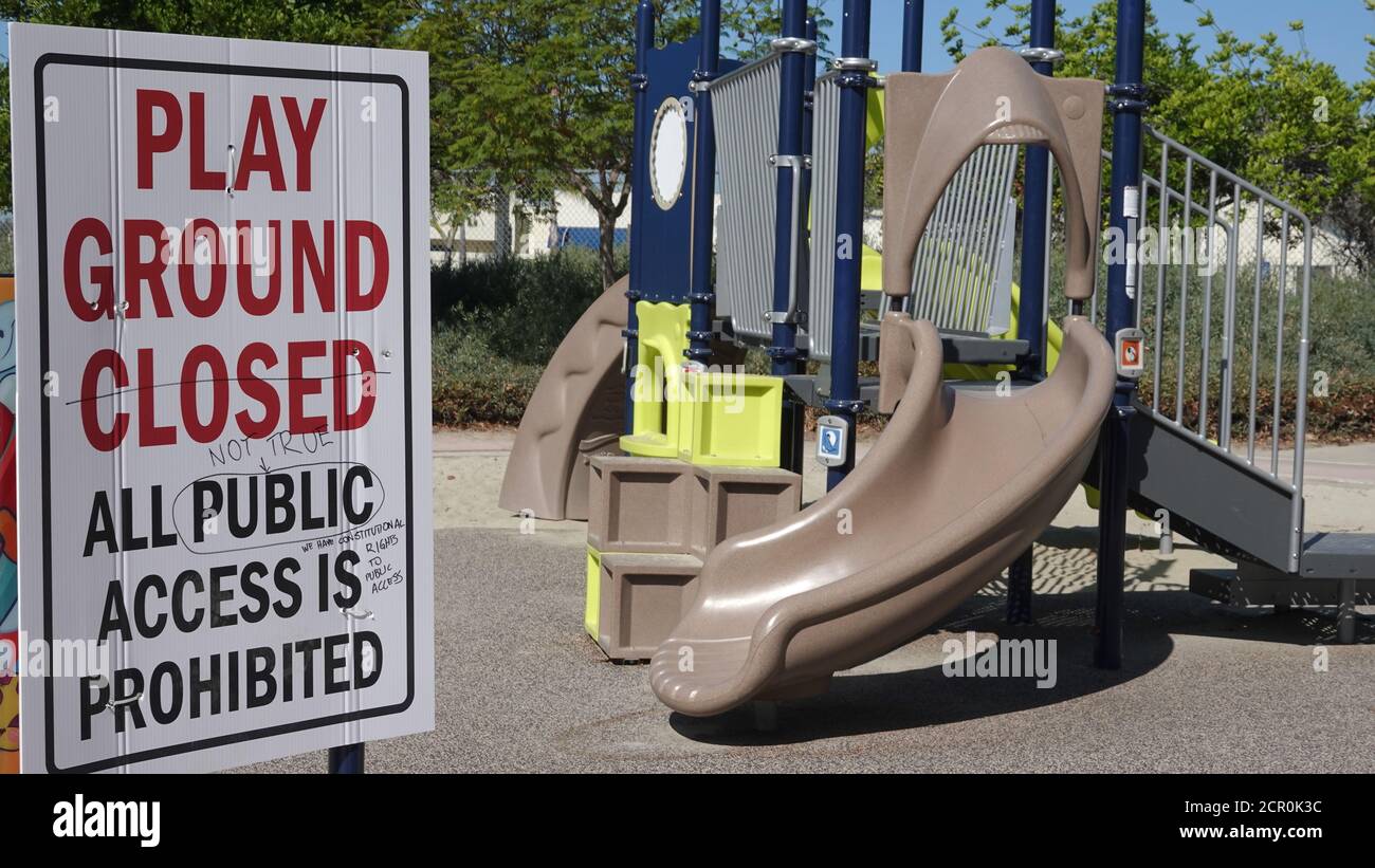 Someone has scribbled notes of protest on a closed playground sign during Covid-19 shutdown. Stock Photo