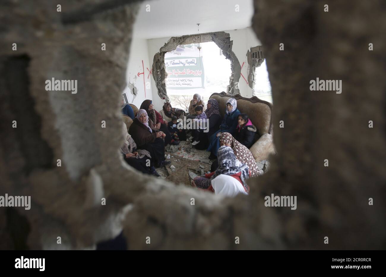Palestinians gather in the home of Mohammed al-Haroub after it was partially demolished by Israeli army in the West Bank village of Dir Samt, south of Hebron February 23, 2016.  Israeli army bulldozers on Tuesday demolished the homes of two Palestinians who killed five people in attacks in the occupied West Bank and Israel last year, the military said. Mohammed al-Haroub shot at cars near an Israeli settlement bloc in the West Bank on Nov. 20, the military said, killing an Israeli, an American student and a Palestinian. REUTERS/Mussa Qawasma Stock Photo