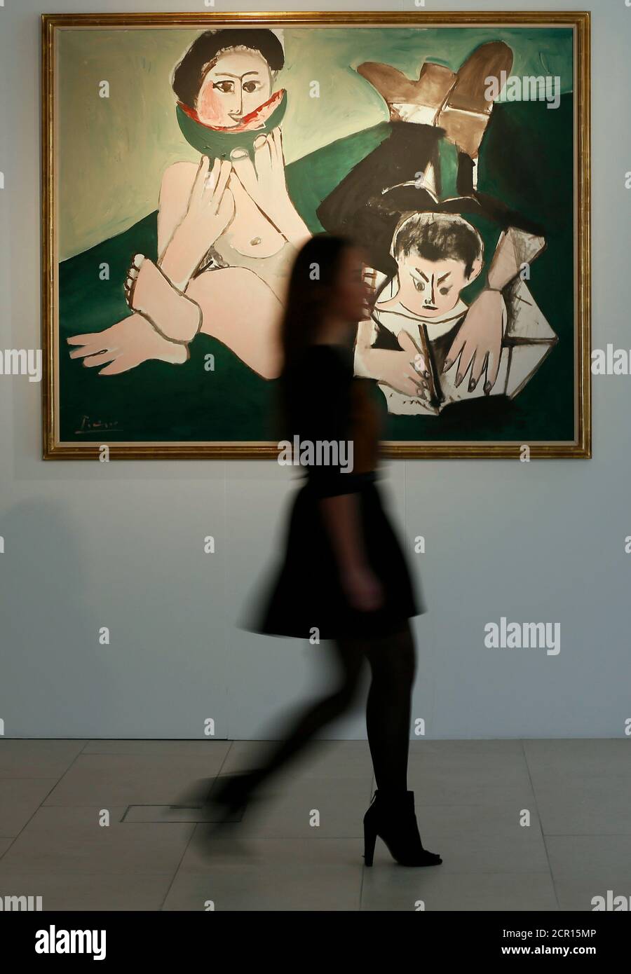 An employee poses with 'Mangeuse de pasteque et homme ecrivant' by Pablo Picasso from 1965, on display at Christie's auction house in London March 28, 2014. The painting is expected to earn 4.2-6 million GB pounds (7-10 million U.S. dollars) when auctioned in New York on May 6.  REUTERS/Stefan Wermuth (BRITAIN- Tags: ENTERTAINMENT BUSINESS) Stock Photo