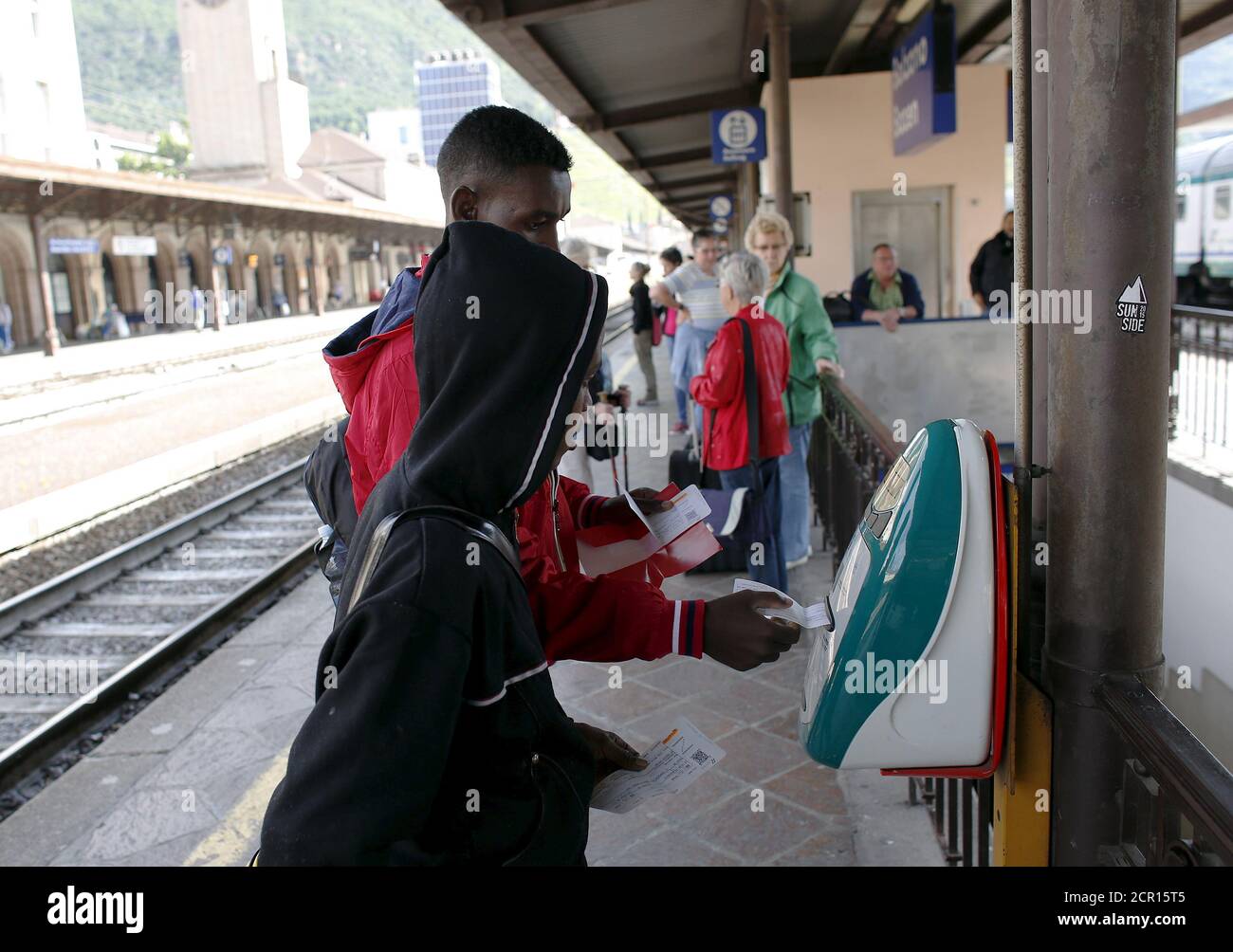 Migrants validate their train tickets at the Bolzano railway station, northern Italy, May 28, 2015. EU asylum rules, known as the Dublin Regulation, were first drafted in the early 1990s and require people seeking refuge to do so in the European country where they first set foot. Northern European countries defend the policy as a way to prevent multiple applications across the continent. Some are upset with what they see as Italy's lax attitude to registering asylum seekers. Earlier this year, French police stopped about 1,000 migrants near the border and returned them to Italy. Smaller round- Stock Photo