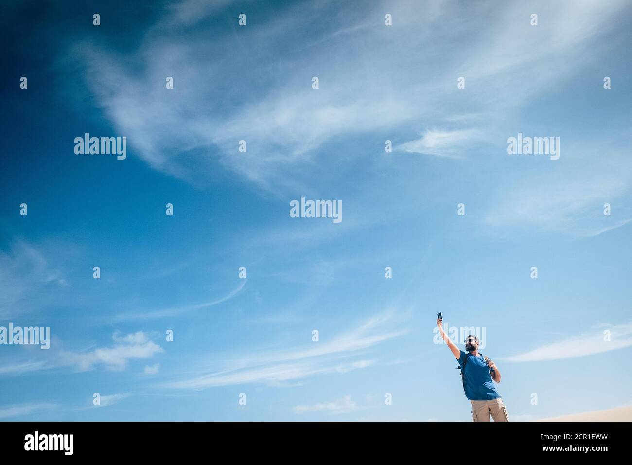 Standing man in outdoor leisure activity check phone internet signal to communicate - concept of internet phone device and communication time in the Stock Photo