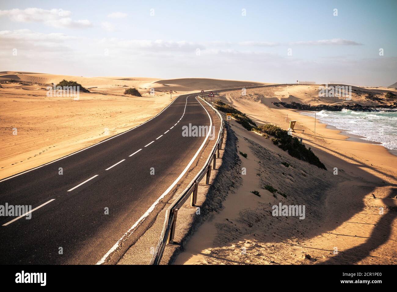 Long black asphalt road with desert and beach around for travel and adventure summer lifestyle concept with nobody traveling and no traffic cars - Stock Photo