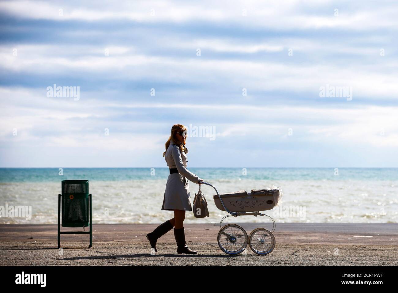 A woman pushes a pram along the embankment in the Black Sea resort town of Alushta March 11, 2014. Ukraine's Crimean peninsular evokes in many Russians and citizens of the former Soviet Union memories of summer holidays in the resorts and sanatoriums along its subtropical Black Sea coast. Crimea is also the place from where Christianity spread throughout what was then called Kievan Rus', a federation of Slavic tribes that later became Russia.  REUTERS/Thomas Peter (UKRAINE - Tags: POLITICS SOCIETY TRAVEL TPX IMAGES OF THE DAY) Stock Photo