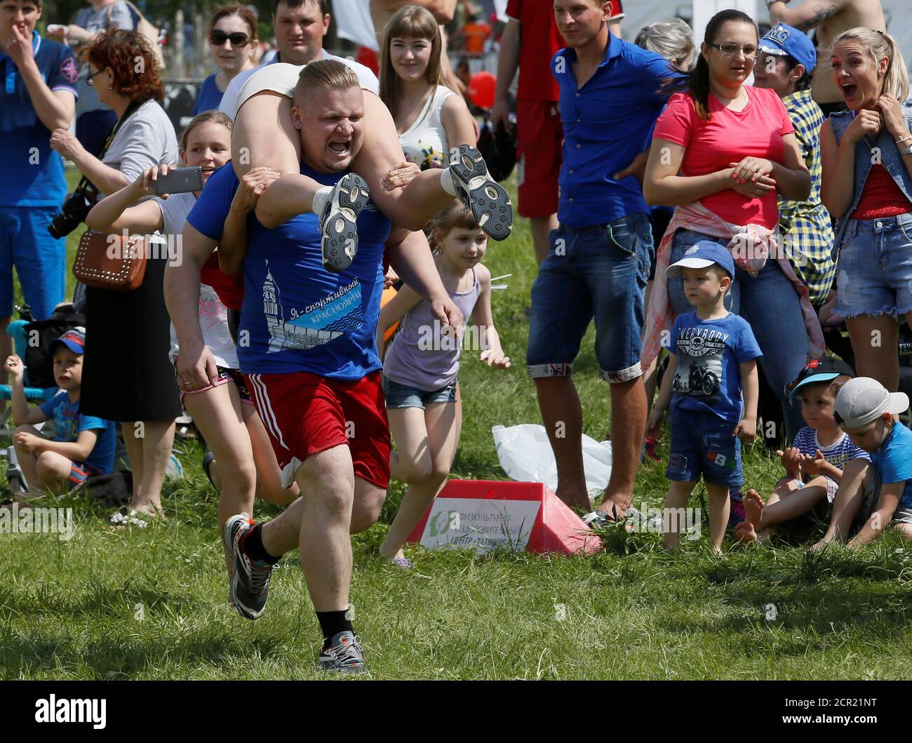 A man carries his wife while racing in the Wife Carrying competititon to mark the City Day in Krasnoyarsk, Siberia, Russia, June 10, 2017. Picture taken June 10, 2017. REUTERS/Ilya Naymushin Stock Photo