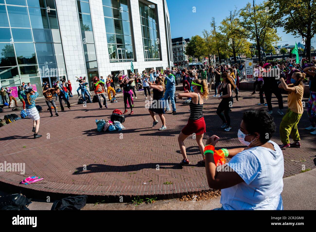 Hundreds of climate activists are seen dancing in front of the city council during the rally.During the whole month, the climate activists group Extinction Rebellion in The Netherlands has planned a new campaign called 'September Rebellion' to draw attention to the climate and ecological crisis. At the Museumplein, in Amsterdam, hundreds of XR activists danced to demand action against climate change in what protesters dubbed “civil disco-bedience”. Activists waved flags and danced to songs including the Bee Gees’ 1977 hit, Stayin’ Alive. After the Museumplein the activists blocked for a few mi Stock Photo