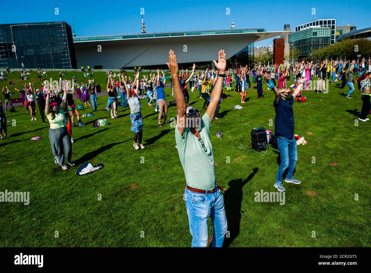 Hundreds of activists are seen dancing while raising their hands during the rally.During the whole month, the climate activists group Extinction Rebellion in The Netherlands has planned a new campaign called 'September Rebellion' to draw attention to the climate and ecological crisis. At the Museumplein, in Amsterdam, hundreds of XR activists danced to demand action against climate change in what protesters dubbed “civil disco-bedience”. Activists waved flags and danced to songs including the Bee Gees’ 1977 hit, Stayin’ Alive. After the Museumplein the activists blocked for a few minutes one o Stock Photo