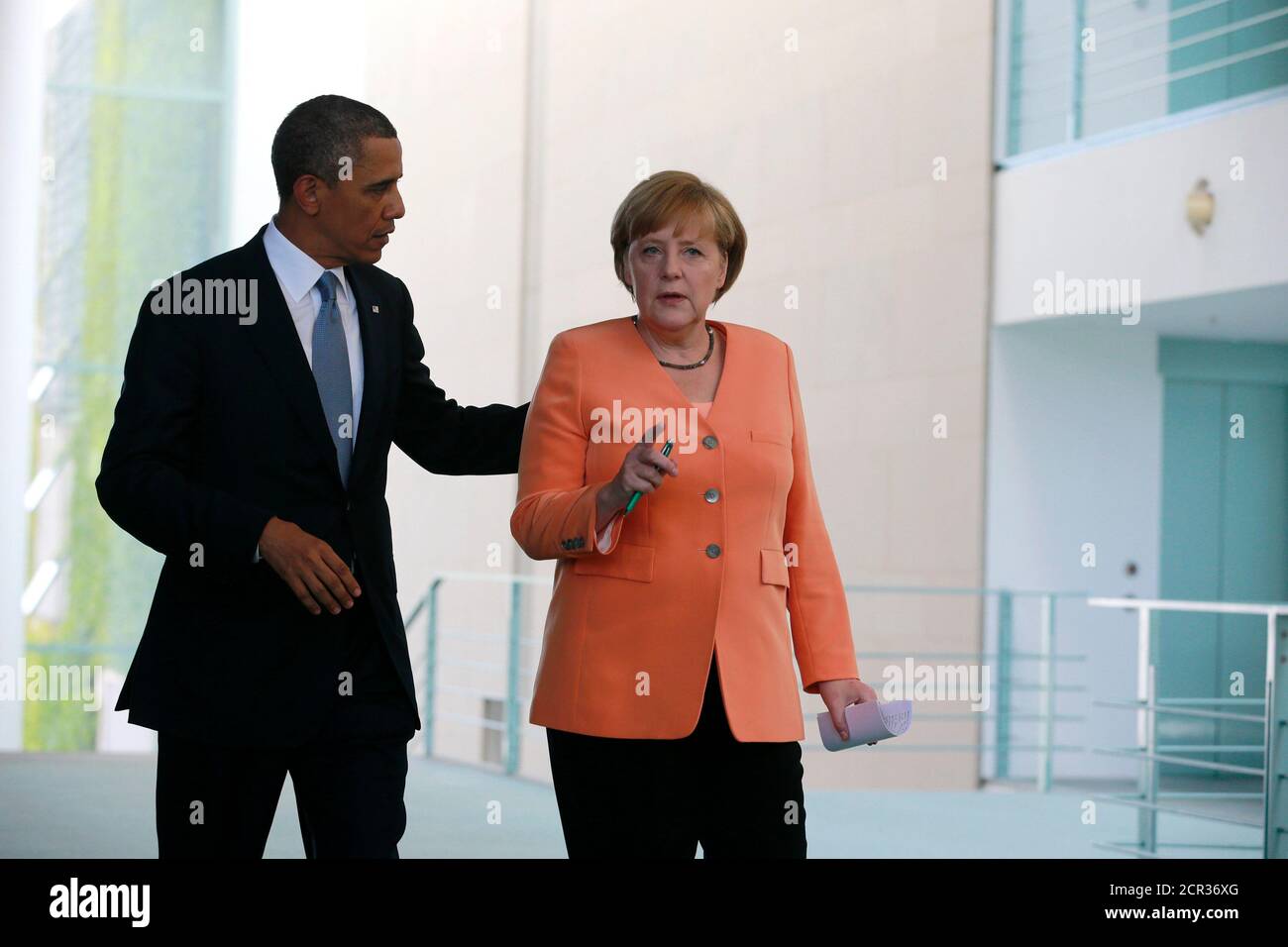 U.S. President Barack Obama and German Chancellor Angela Merkel (R) make their way to a news conference at the Chancellery in Berlin June 19, 2013. Obama will unveil plans for a sharp reduction in nuclear warheads in a landmark speech at the Brandenburg Gate on Wednesday that comes 50 years after John F. Kennedy declared 'Ich bin ein Berliner' in a defiant Cold War address.        REUTERS/Thomas Peter (GERMANY  - Tags: POLITICS) Stock Photo