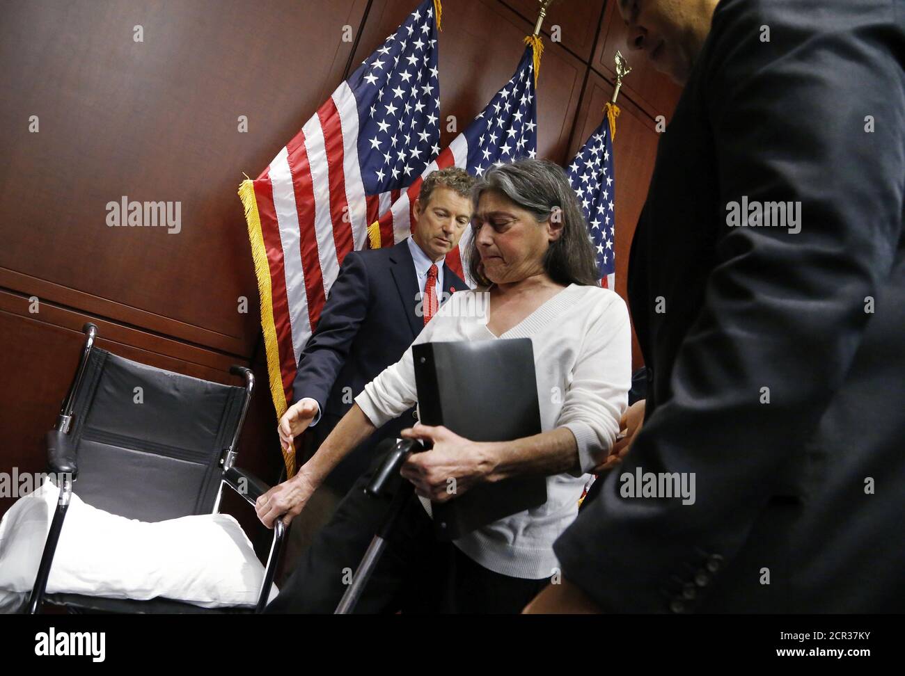 U.S. Senator Rand Paul (R-KY) (L) and Senator Cory Booker (D-NJ) (R) help Sandy Faiola, a medical marijuana patient from New Jersey, to her wheelchair at a news conference, to introduce legislation that would prevent the federal government from prosecuting medical marijuana users in states where it is legal, at the U.S. Capitol in Washington, March 10, 2015. REUTERS/Jonathan Ernst    (UNITED STATES - Tags: POLITICS HEALTH SOCIETY) Stock Photo