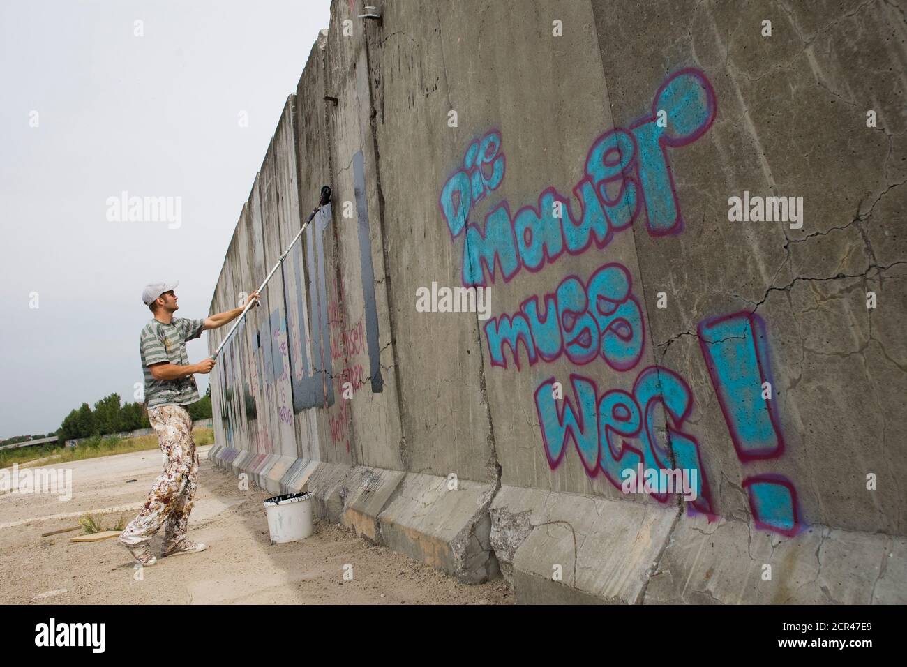 A Graffiti Artist Paints Words Onto A Segment Of The Berlin Wall Near The Former Border