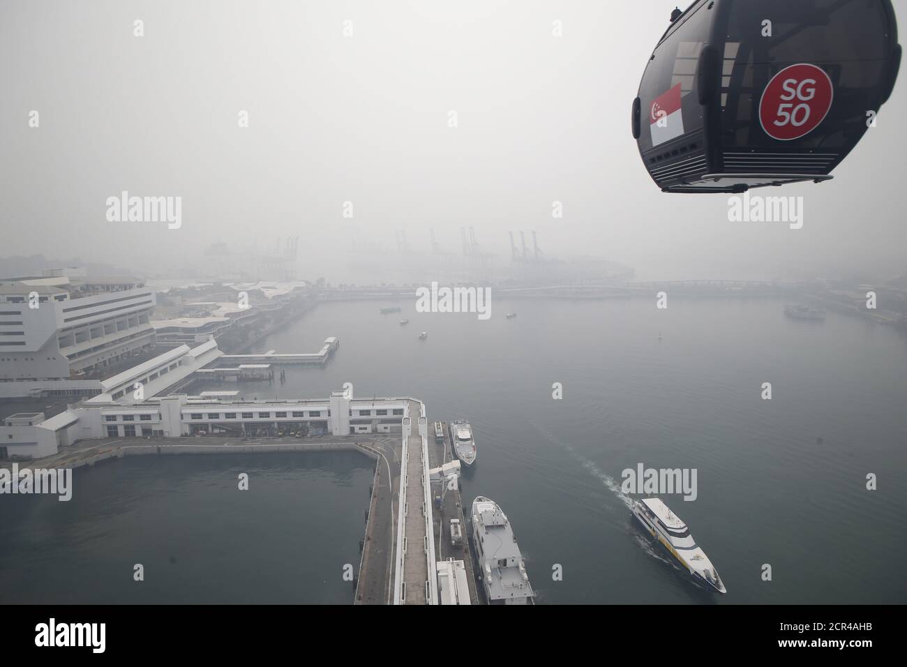 A cable car travelling between Mount Faber and Sentosa passes the skyline of the central business district and PSA International's Keppel and Brani container terminals shrouded by haze in Singapore September 29, 2015. The 3-hour haze Pollutant Standards Index (PSI) was at 205 at 11am on Tuesday, according to the National Environment Agency. Slash-and-burn agriculture in neighbouring Indonesia has blanketed Singapore in a choking haze for weeks.   REUTERS/Edgar Su Stock Photo