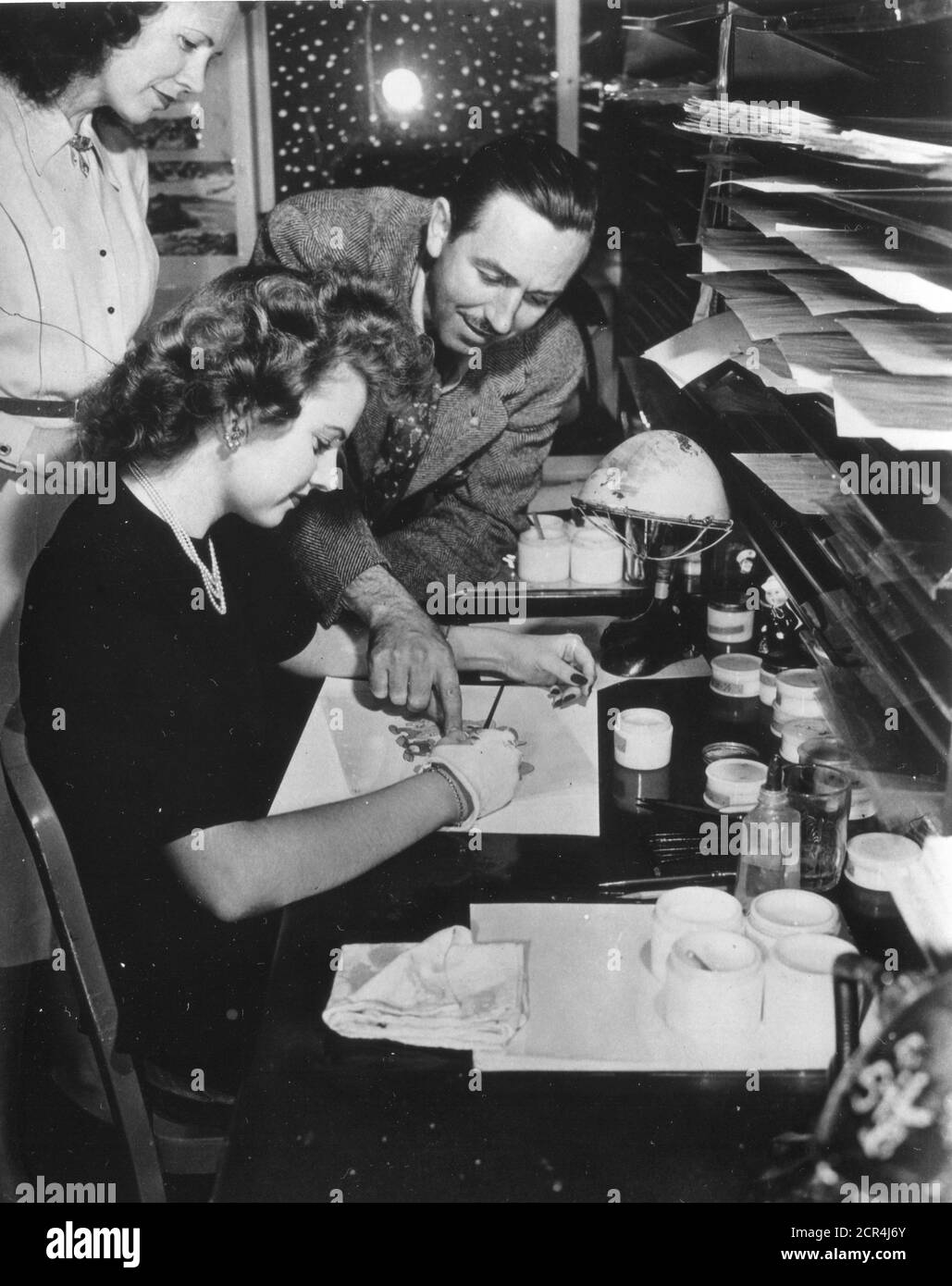 Walt Disney (right) gives painter Edith Moore advice on painting the finished celluloids which are photographed to make a Disney film, Burbank, CA, 1943. (Photo by Office of War Information/RBM Vintage Images) Stock Photo