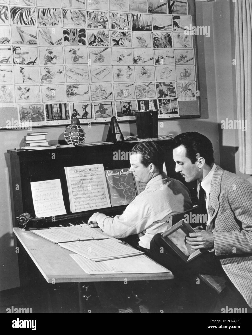 Disney composer Charles Wolcott (1906-1987) at the piano rehearses a song from Saludos Amigos with Brazilian singer Aloysio de Oliveira (1914-1995), Burbank, CA, 1943. (Photo by Office of War Information/RBM Vintage Images) Stock Photo
