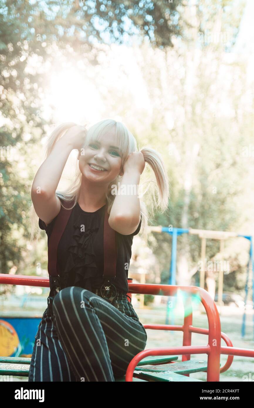 Beautiful blond girl with long hair on playground with blurred background, sun flare in frame. Stock Photo
