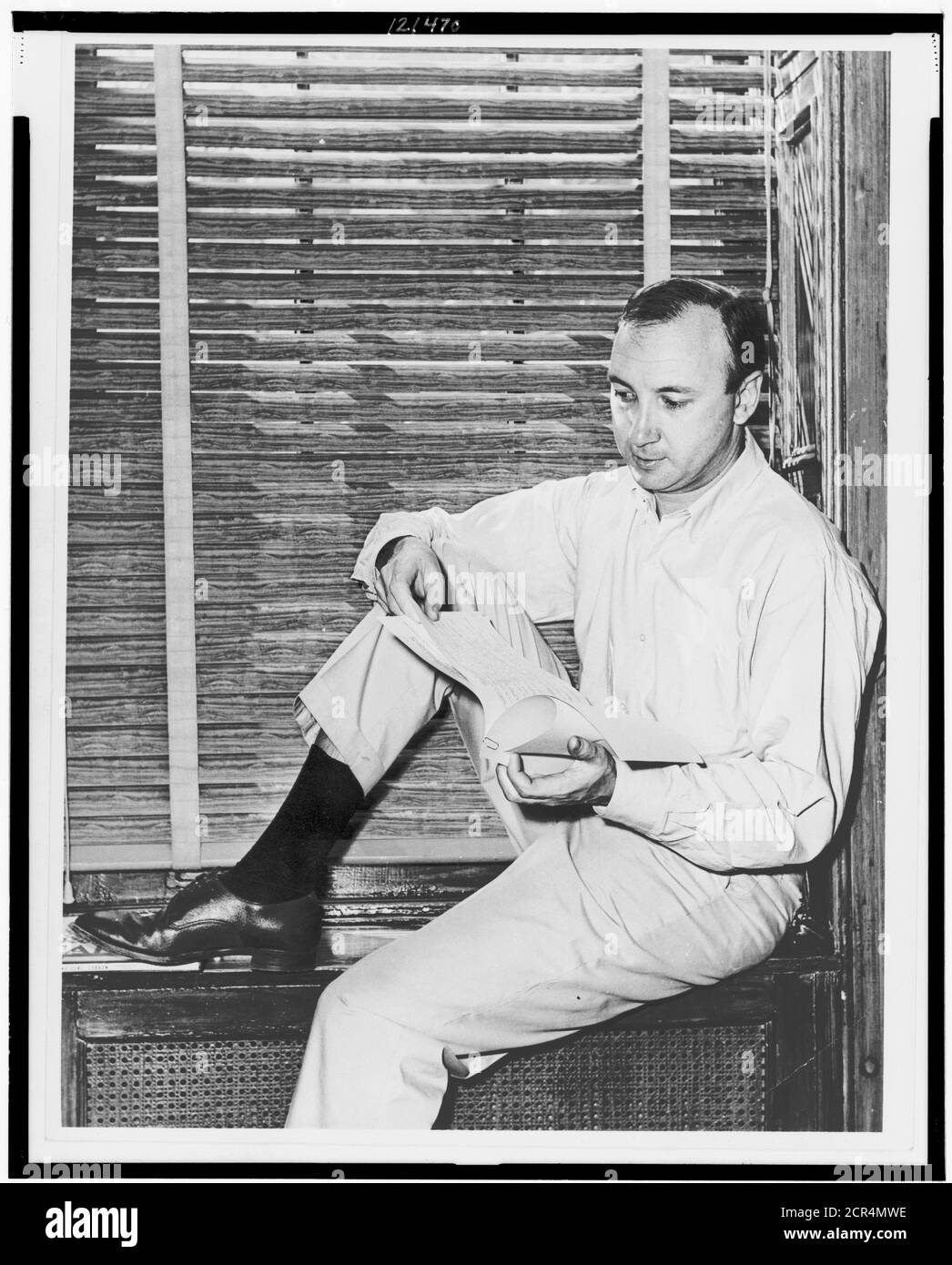 Pulitzer Prize-winning author and playwright Neil Simon sitting on a windowsill at home poring over the script of a play he wrote, New York, NY, 1966. (Photo by Al Ravenna/RBM Vintage Images) Stock Photo