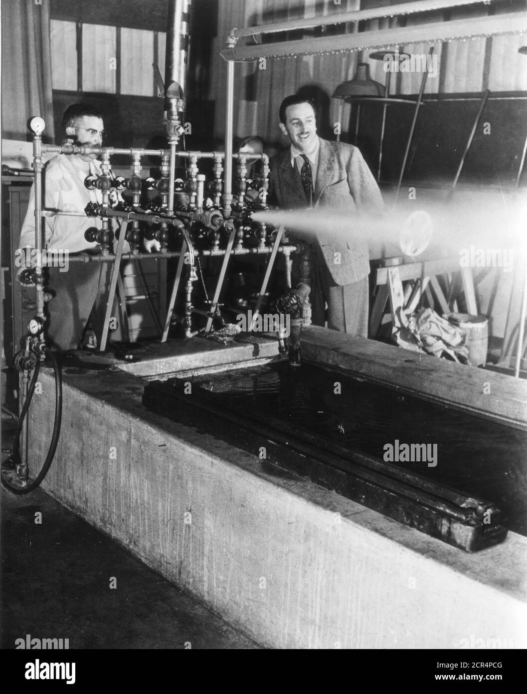 In the sound effects studio, Walt Disney examines an intricate steam-producing machine which, when properly recorded, becomes a whistle blast, Burbank, CA, 1943. (Photo by Office of War Information/RBM Vintage Images) Stock Photo