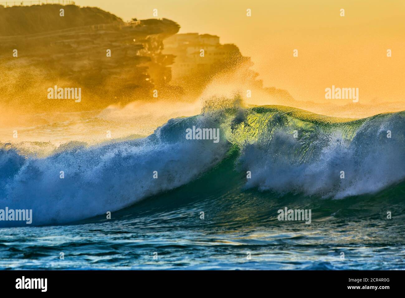 Rolling fluid emerald wave in bright soft morning light off Bronte beach in Sydney. Stock Photo