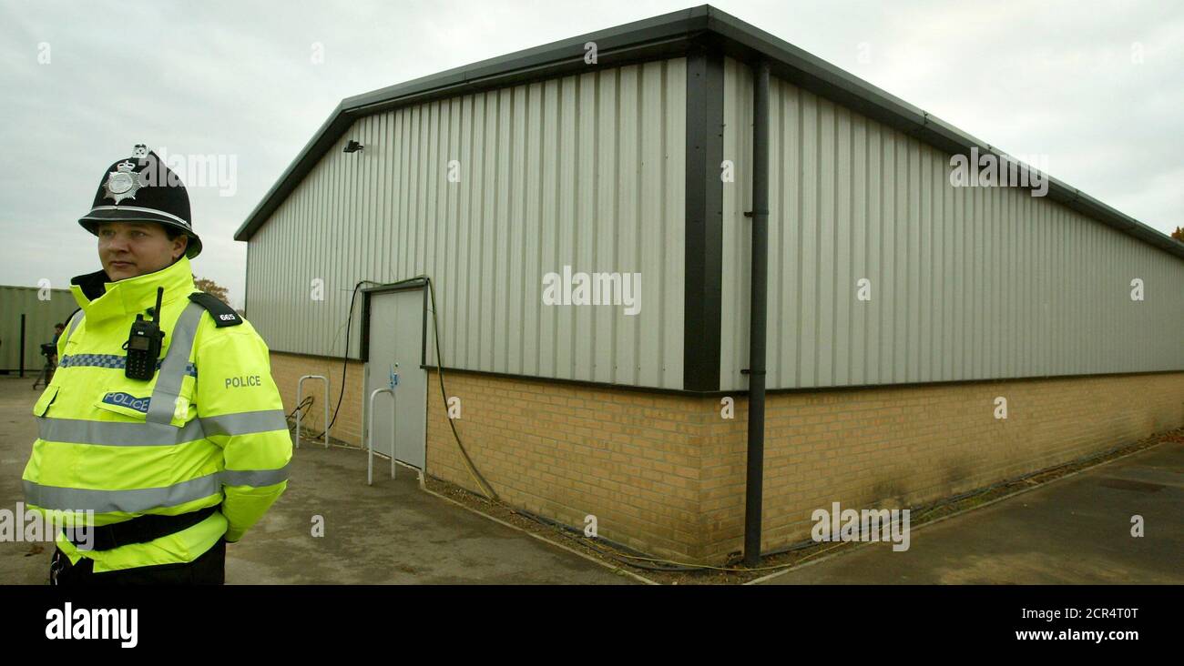 A British police officer stands guard at the sealed hangar building, in the grounds of Soham Village College where the burnt clothes of murdered Soham schoolgirls Jessica Chapman and Holly Wells were discovered in Cambridgeshire, south east England, November 10, 2003. The jury were taken to various sites on Monday including the house at number 5 College Close, where the man charged with the murders, former school caretaker Ian Huntley, lived and prosecutors say murdered the two schoolgirls last August. REUTERS/Peter Macdiarmid  PKM/MD/JV Stock Photo