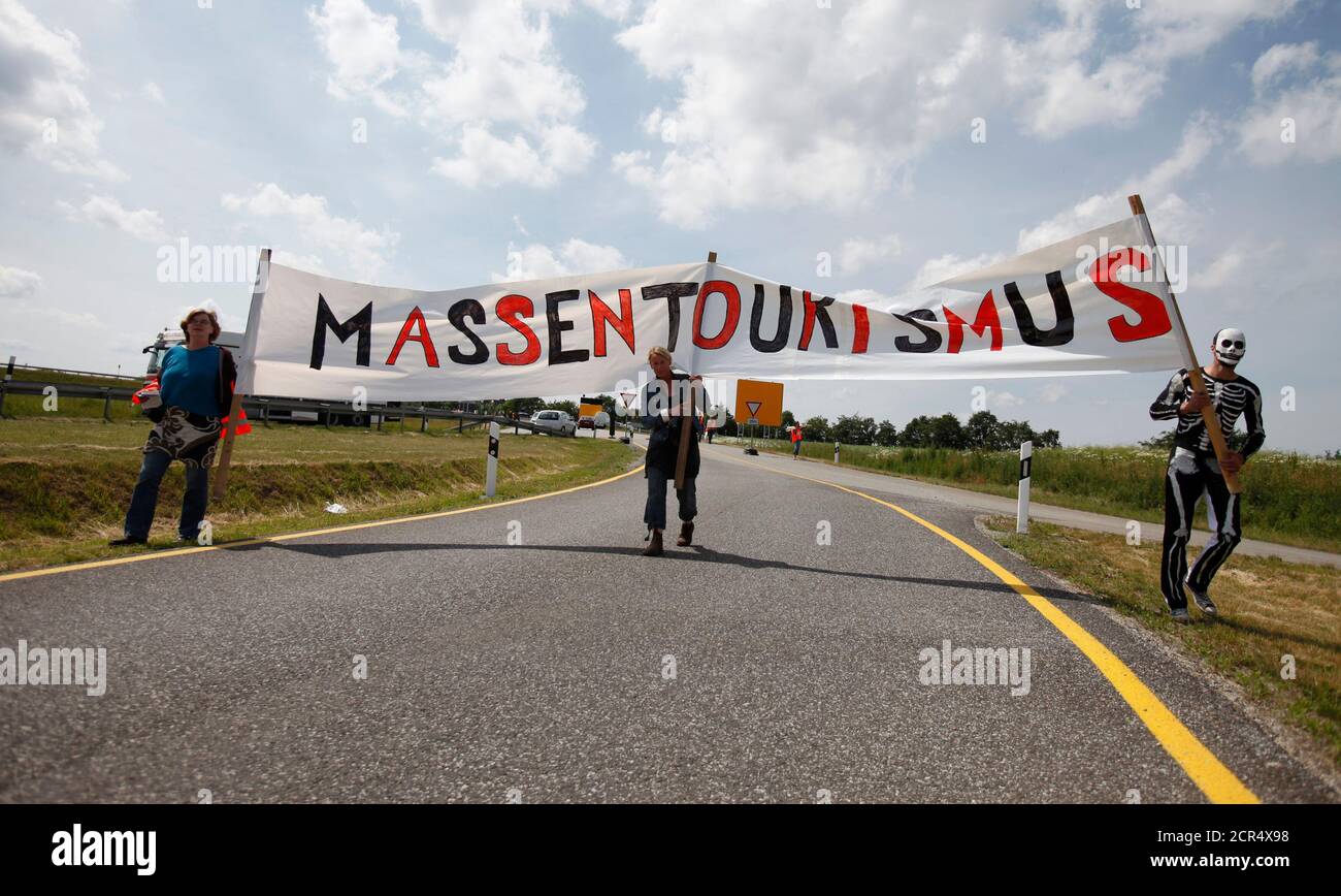 B96n highway opponents arrive at the ground-breaking ceremony for the infrastructure project near Altefaehr on Ruegen Island, June 15, 2011.  The banner reads: 'mass tourism.'REUTERS/Thomas Peter (GERMANY - Tags: POLITICS TRANSPORT CIVIL UNREST) Stock Photo
