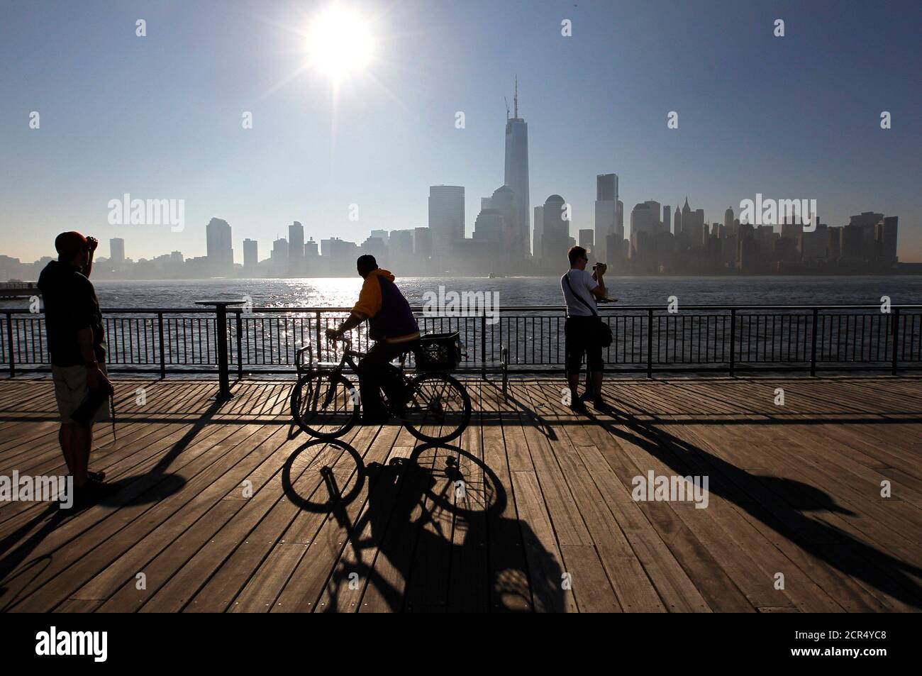 People look out at the Lower Manhattan skyline from a promenade next to the  Hudson River in Jersey City, New Jersey May 8, 2013. New York City is  iconic in any weather,