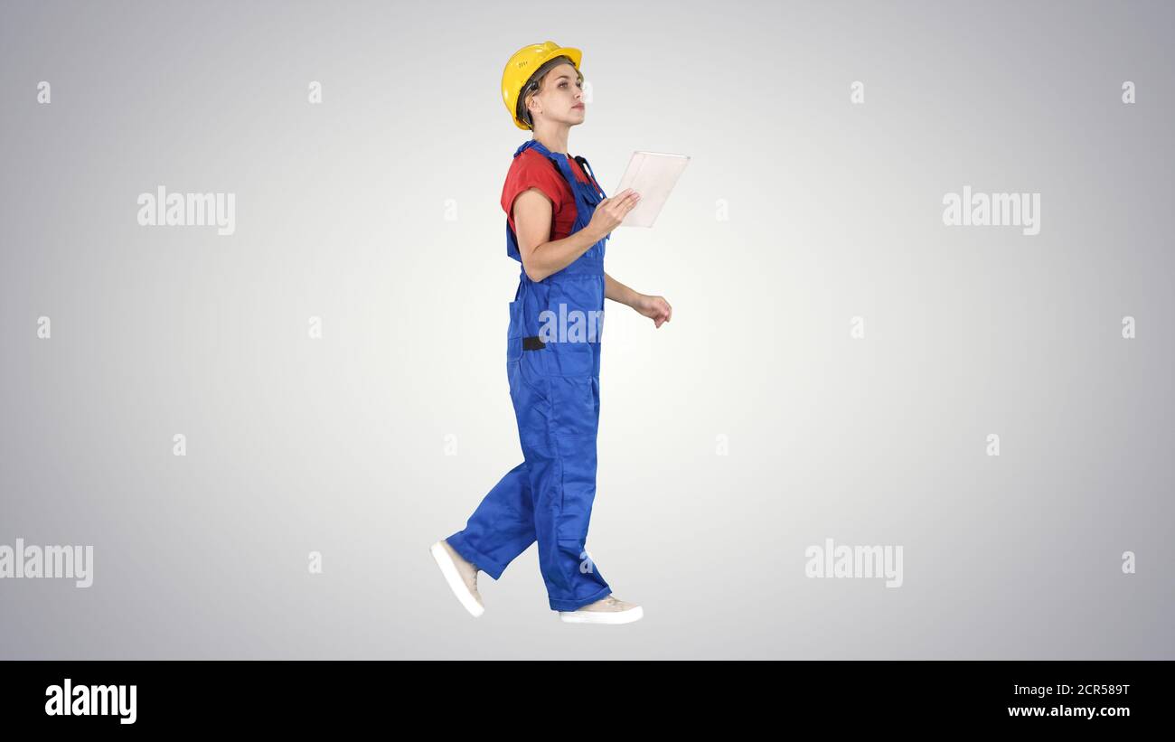 Construction lady using electronic tablet walking on gradient ba Stock Photo