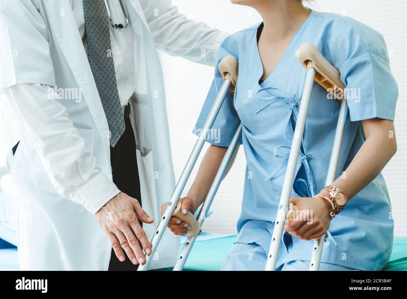 Doctor takes care of patient in crutch at hospital. Physical therapist