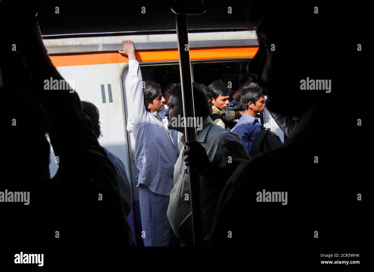 Passengers Ride At The Open Doorways Of Commuter Trains During The Morning Rush Hour In Mumbai