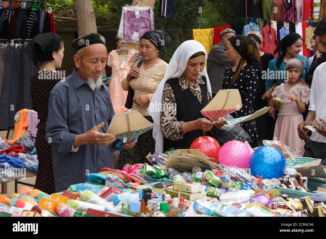 Husband and wife examining straw fans at Tuyugou street market, near Flaming Mountains, Turpan