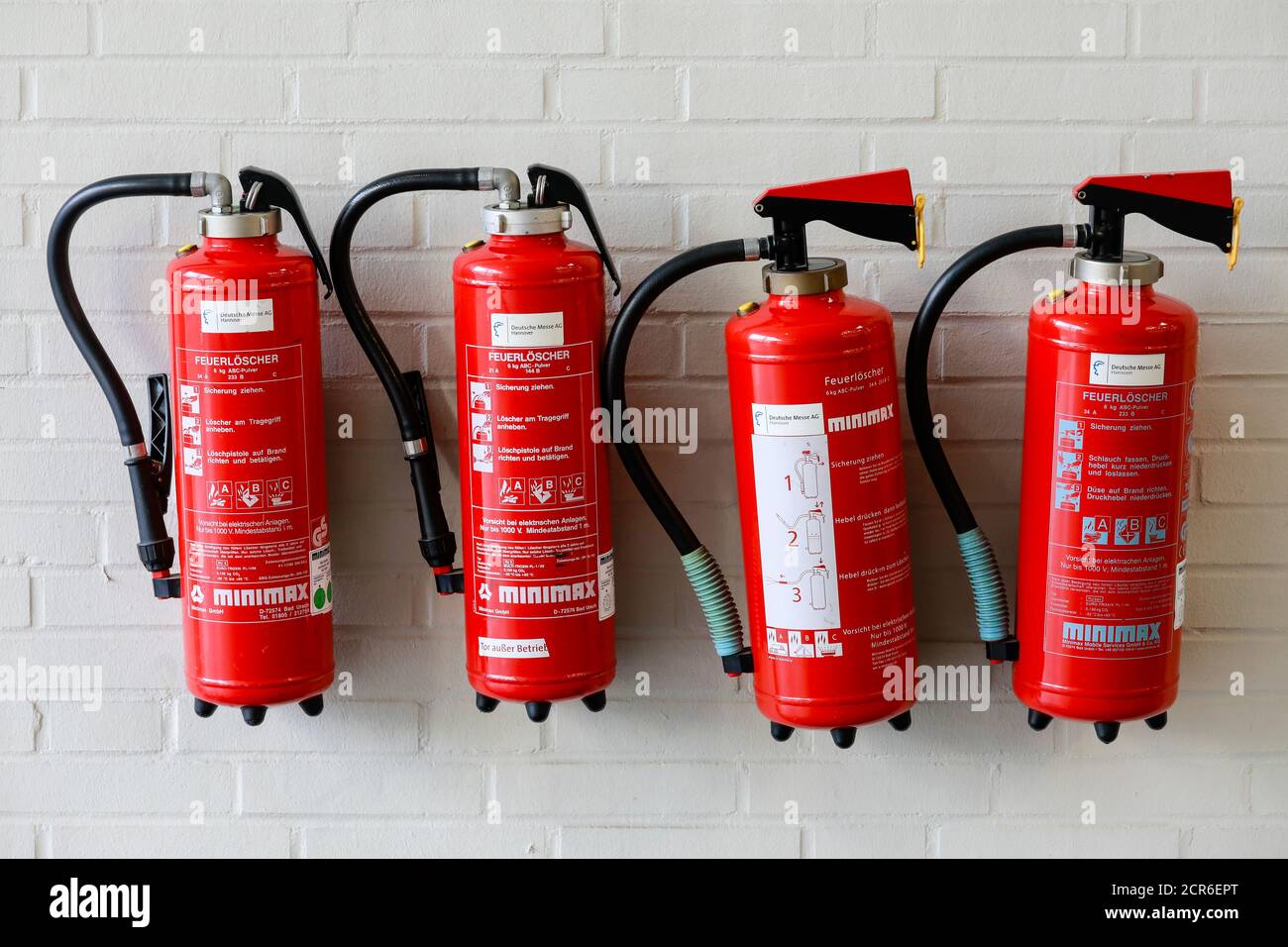 Hannover, Lower Saxony, Germany - Four red fire extinguishers on a wall at the Hannover Messe. Stock Photo