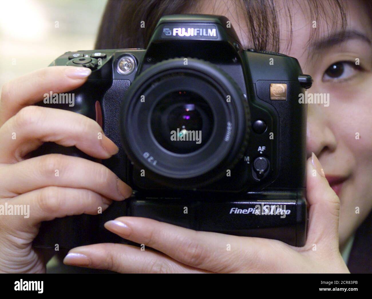Fuji Film worker Kazumi Hiraiwa demonstrates the newly developed 6.1 megapixel digital SLR camera FinePix S1Pro in Tokyo January 31. The camera features a 23.3x15.6-mm Super CCD bringing 6.1 million pixels (3,040x2,016) and works with the F mount Nikon lenses. The camera has two slots for storage media of SmartMedia, CompactFlash card and IBM microdrive. The camera targeted for professional photographer has a range of shutter speeds from 30 seconds to 1/2,000 seconds with 1.5 frames per second and offers four equivalent ISO sensitivity from 320 to 1600. Fuji Film said the camera will be on sal Stock Photo