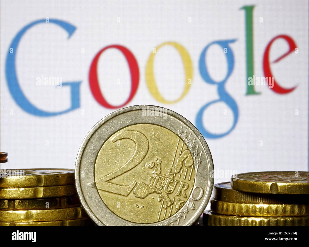 Euro coins are seen in front of a Google logo in this picture illustration taken in Zenica, April 21, 2015. The European Union accused Google Inc on Wednesday of cheating competitors by distorting Internet search results in favour of its Google Shopping service and also launched an antitrust probe into its Android mobile operating system. This logo has been updated and is no longer in use.   REUTERS/Dado Ruvic Stock Photo