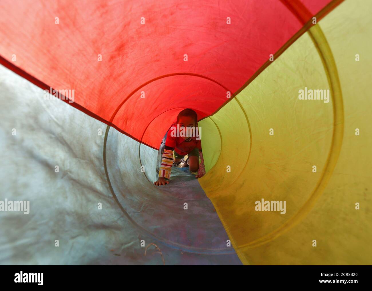A boy looks on as he crawls through a play tunnel during a rugby training session at a public park in Kolkata, India, December 28, 2015. REUTERS/Rupak De Chowdhuri Stock Photo