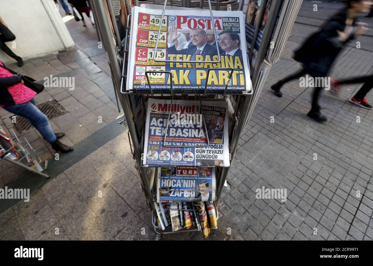 People walk past by a kiosk in central Istanbul, Turkey November 2, 2015. A jubilant President Tayyip Erdogan on Monday cast the return of Turkey's Islamist-rooted AK Party to single-party rule as a vote for stability that the world must respect, but opponents fear it heralds growing authoritarianism and deeper polarisation. The newspaper headline on top reads: 'AK Party on its own' REUTERS/Murad Sezer Stock Photo