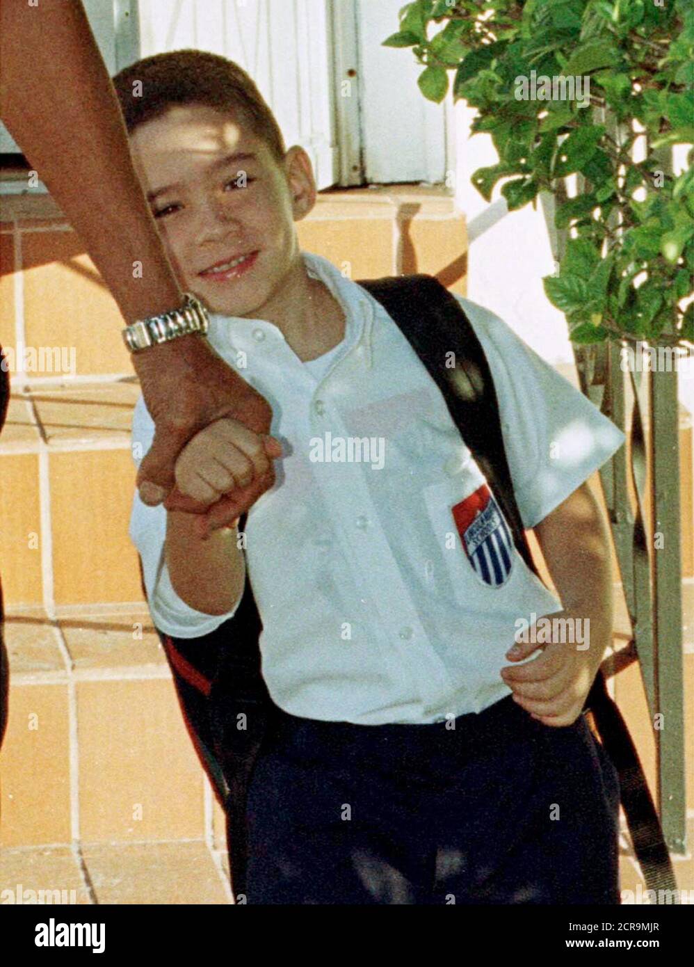 Cuban boy Elian Gonzalez holds on to the hand of his great uncle Lazaro Gonzalez as he goes to school January 12. Elian has been living with relatives since he was rescued at sea November 25 after spending two days clinging to an innertube. The Justice Department is standing by a federal ruling that would send 6-year-old Elian Gonzalez back to Cuba to be with his father. Attorney General Janet Reno said the state court had no authority "to say who speaks for the boy in a federal immigration matter" and is prepared to litigate the matter in federal court. The boy's mother, stepfather and 10 oth Stock Photo