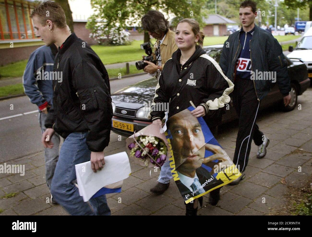 Supporters of Dutch politician Pim Fortuyn carry his campaign posters and  flowers after the maverick Dutch anti-immigration politician was shot dead  on May 6, 2002, nine days before a general election in