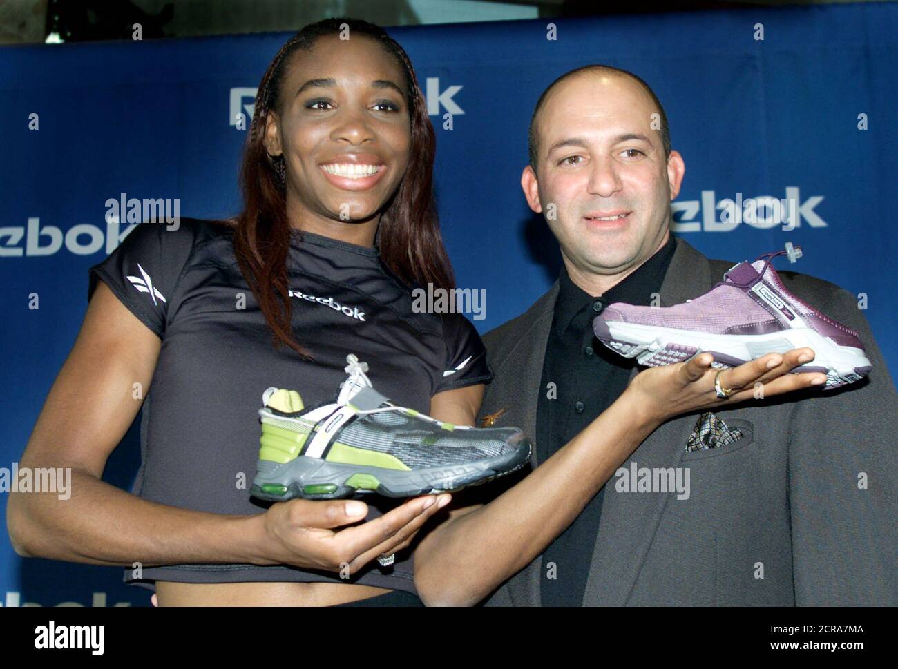 Tennis star Venus Williams holds up her signature Venus Williams Reebok  tennis shoes next to Reebok International Ltd. Vice President Angel  Martinez at a news conference in New York, December 21, 2000,