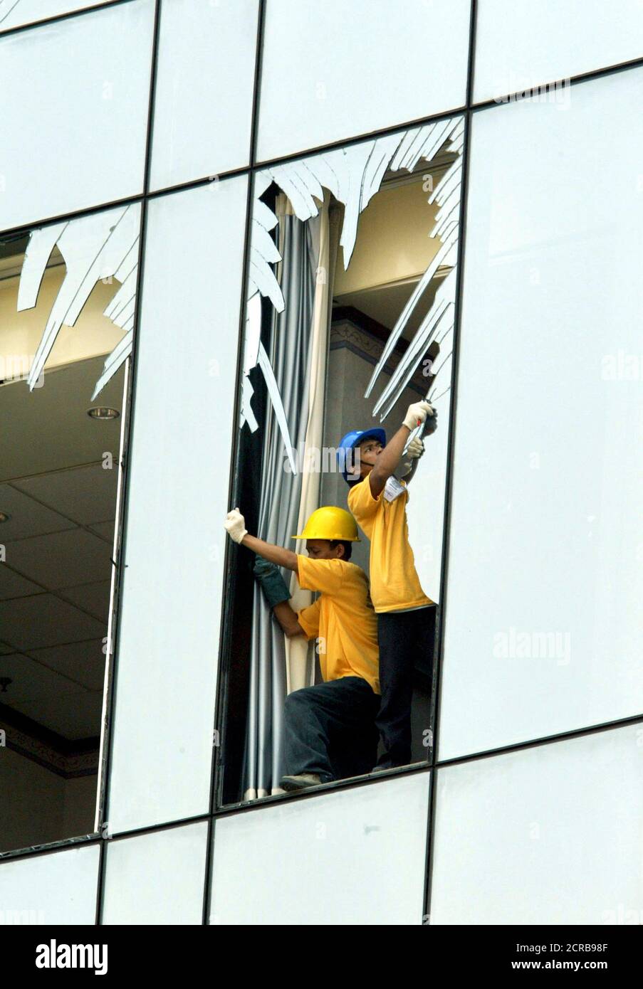 Indonesian workers remove glass shards from a window of the JW Marriot Hotel in Jakarta August 13, 2003. Indonesia will likely strengthen anti-terrorism regulations to prevent more attacks such as last week's bomb blast at the hotel that killed more than 10 people, but will not copy draconian security laws used by its neighbours, an official said on Wednesday. REUTERS/Beawiharta  EN/FA Stock Photo