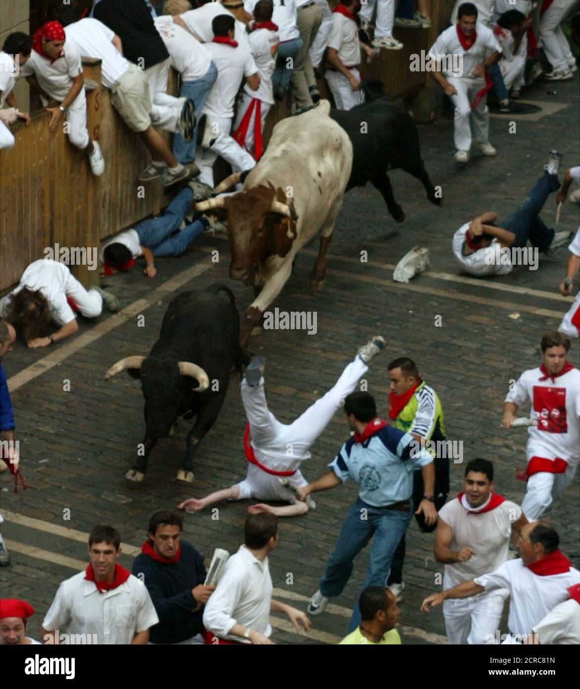 British bull runner David Bigging lands upside down after being gored and tossed by a bull during the sixth running of the bulls of the San Fermin festival in Pamplona on July 12, 2003. A pack of six fighting bulls and steers runs through the centre of the town to the bullring every morning during the week long festival made famous by U.S. writer Ernest Hemingway. Bigging suffered a 10 centimetre (four inch) wound in his upper right thigh as well as a blow to the head, but was not in serious condition, the Navarra regional government said REUTERS/Paul Hanna  PH/JV Stock Photo