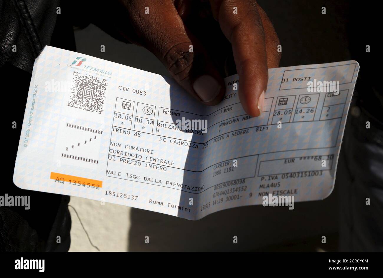 A migrant shows his train ticket to Germany, as he waits to take the train from the Italian border at Bolzano railway station, Italy May 28, 2015. EU asylum rules, known as the Dublin Regulation, were first drafted in the early 1990s and require people seeking refuge to do so in the European country where they first set foot. Northern European countries defend the policy as a way to prevent multiple applications across the continent. Some are upset with what they see as Italy's lax attitude to registering asylum seekers. Earlier this year, French police stopped about 1,000 migrants near the bo Stock Photo