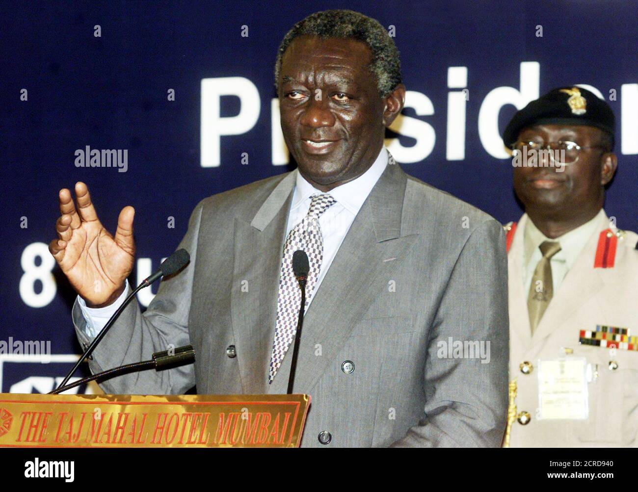 President of Ghana, John Agyekum Kufuor (L) speaks to a gathering of Indian industrialists, as his bodyguard looks on during a meeting by the Confederation of Indian Industry (CII) in Bombay, August 8, 2002. Kufuor is on a six-day official visit to India to attract Indian investments to Ghana. REUTERS/Arko Datta  AD/JS Stock Photo