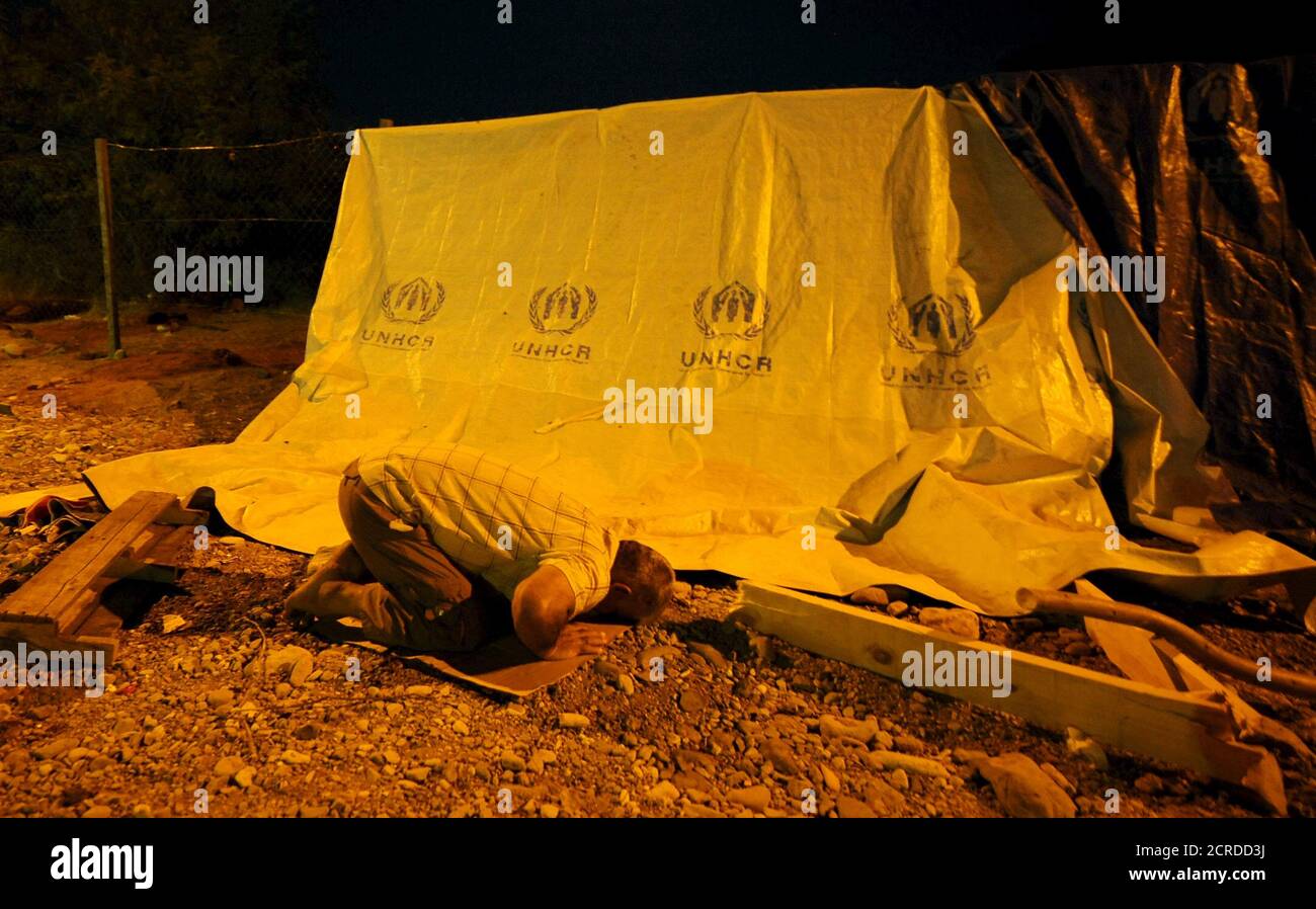 A migrant prays next to a UNHCR tent as he waits to board a northbound train, at Macedonia's south border near Gevgelija August 26, 2015. The train will take them to Macedonia's north border with Serbia, on their way to Western Europe.   REUTERS/Ognen Teofilovski Stock Photo