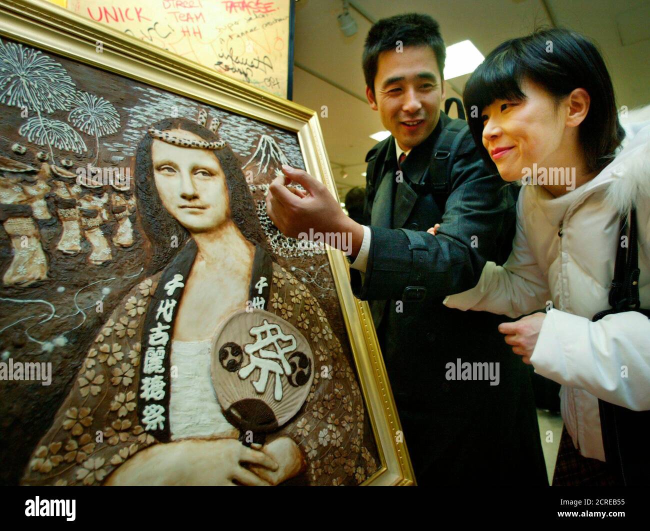 A Japanese couple looks at a 'Mona Lisa' painting made from chocolate on display at Salon du Chocolat in Tokyo January 29, 2004. The creation, made by Japanese chocolate maker Madamu Setsuko, is 77 cm (30.3 inches) in height and 53 cm (20.8 inches) in length and uses 13 kg (28 lb) of chocolate. Picture taken January 29. REUTERS/Haruyoshi Yamaguchi  YN Stock Photo