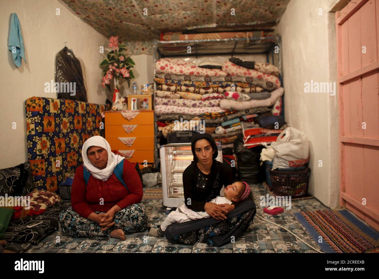 Sevgi Gezici, widow of Engin Gezici, holding her daughter Helin, sits next to her mother-in-law Seviye Gezici (L) at their family house in the southeastern town of Silvan in Diyarbakir province, Turkey, December 7, 2015. The shepherd's widow no longer asks God for peace. Like many Kurds in Turkey's southeast, Sevgi Gezici, 22, believed President Tayyip Erdogan would relent in a violent clampdown against Kurdish militants after his party won back its majority in an election in November. Three days after the vote, her husband, just back from seven months tending sheep, was shot dead in the stree Stock Photo