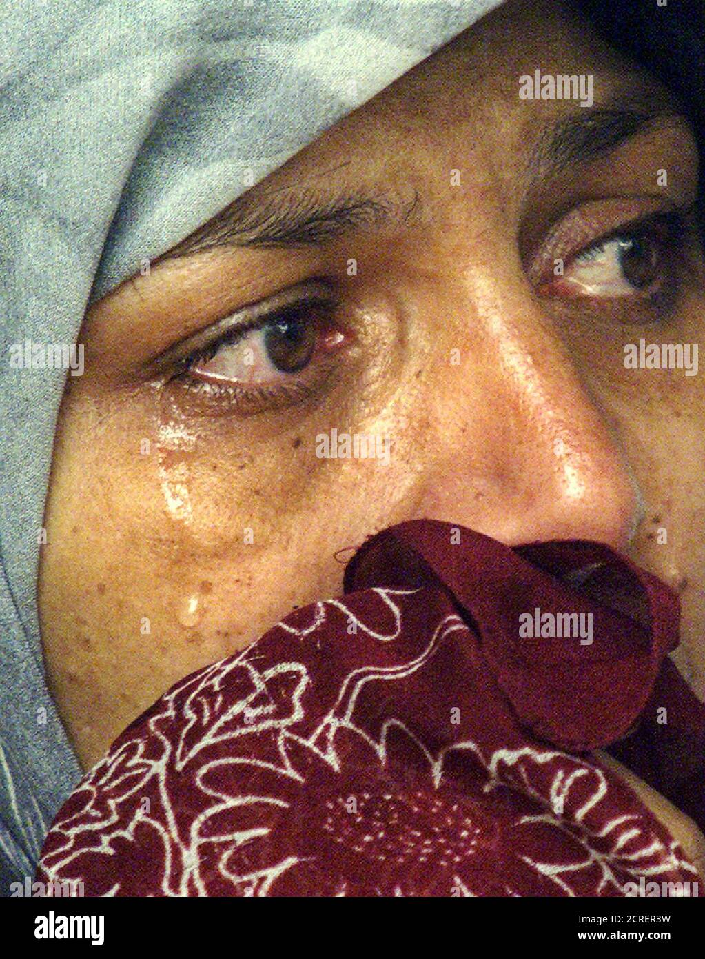 An Afghan woman who didn't want to be named wipes away her tears as she talks to journalists outside the United Nations High Commissioner for Refugees (UNHCR) office in Kuala Lumpur, January 25, 2002. The woman, who is an ethnic Hazara, said she came to Malaysia with her husband and two children four months ago hoping to get refugee status. The woman said her family is now hiding in a village near Kuala Lumpur, and is asking UNHCR to send them home to Afghanistan. Though things are bad in Afghanistan, she said maybe it would be better there than being a fugitive in Malaysia. REUTERS/Bazuki Muh Stock Photo
