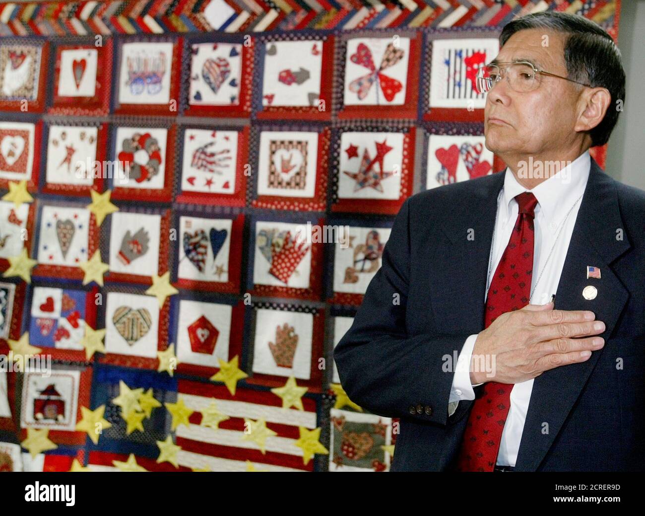 U.S. Secretary of Transportation Norman Mineta stands with his hand over his heart during a 'Hearts and Hands Across the Potomac' quilt dedication ceremony at the Department of Transportation in Washington, August 27, 2002. The quilt was built by department women in honor of those women who died at the Pentagon attack on September 11, 2001 and was presented to the Department of Defense during the ceremony. REUTERS/Larry Downing  LSD Stock Photo