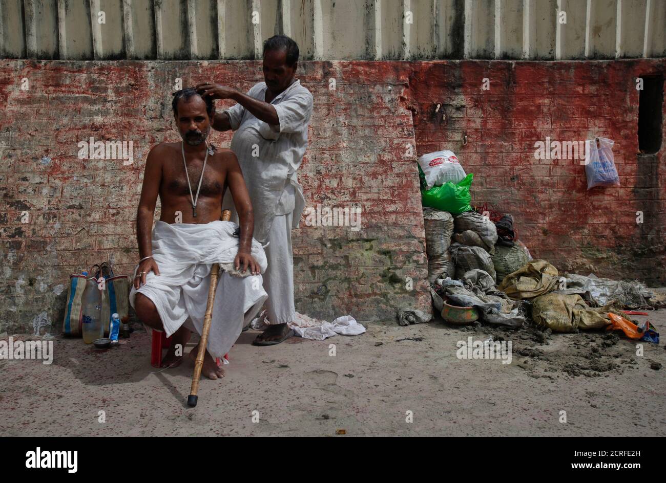 Shibdas, 38, has his head shaved by a barber on the banks of the Ganges river, as part of a Hindu ritual after his father died, in Kolkata September 3, 2011. Many Hindus come to Babughat, a set of bathing steps in Kolkata, to have their heads shaved and to take a dip in the waters as part of the final rites for the deceased.  REUTERS/Vivek Prakash (INDIA - Tags: SOCIETY RELIGION) Stock Photo