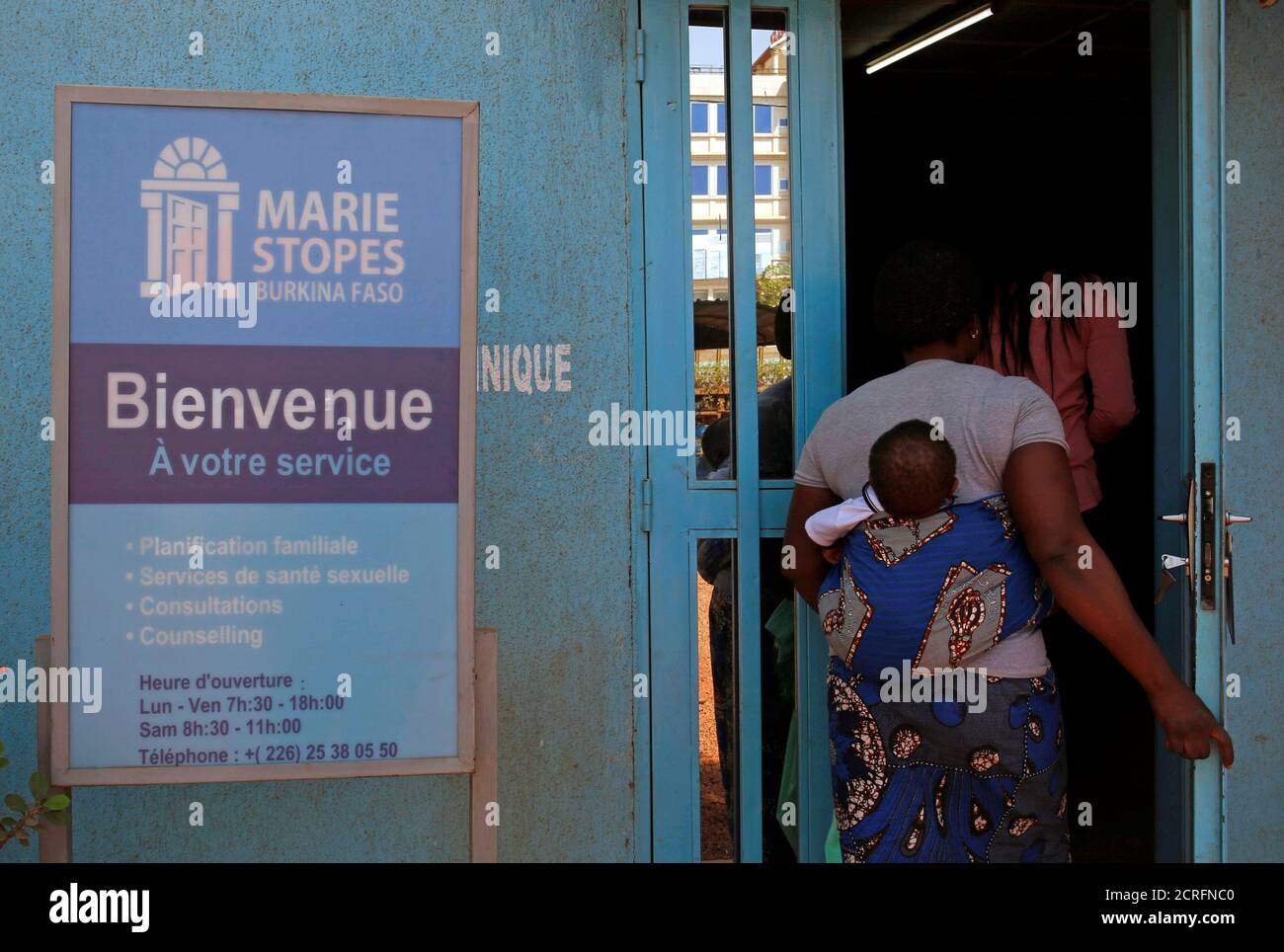 A woman carrying a baby arrives at the clinic of the NGO Marie Stopes in Ouagadougou, Burkina Faso February 16, 2018. Picture taken February 16, 2018. REUTERS/Luc Gnago Stock Photo