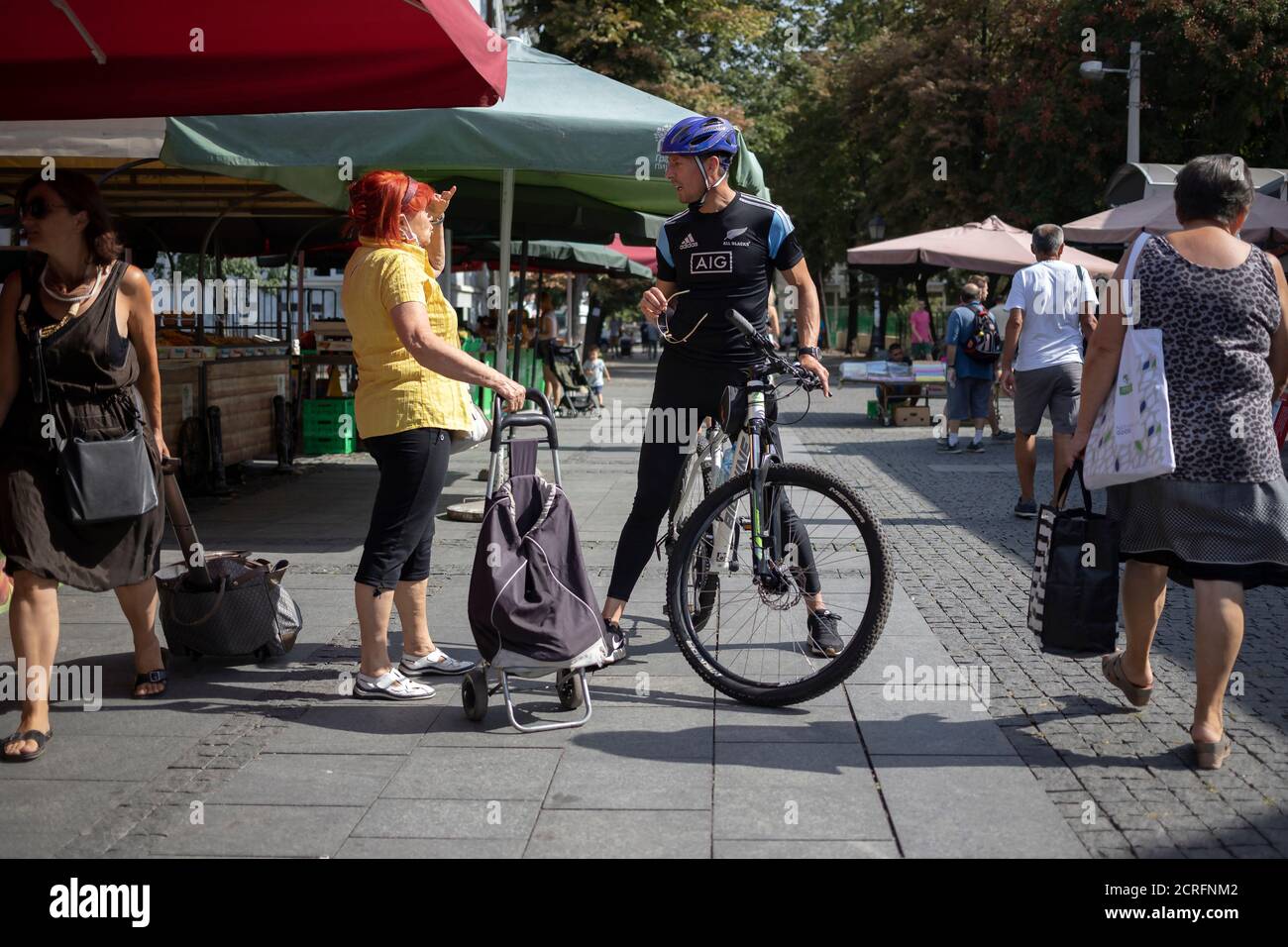 Belgrade, Serbia, Sep 17, 2020: Street scene with a woman chatting with cyclist at farmer’s market Stock Photo